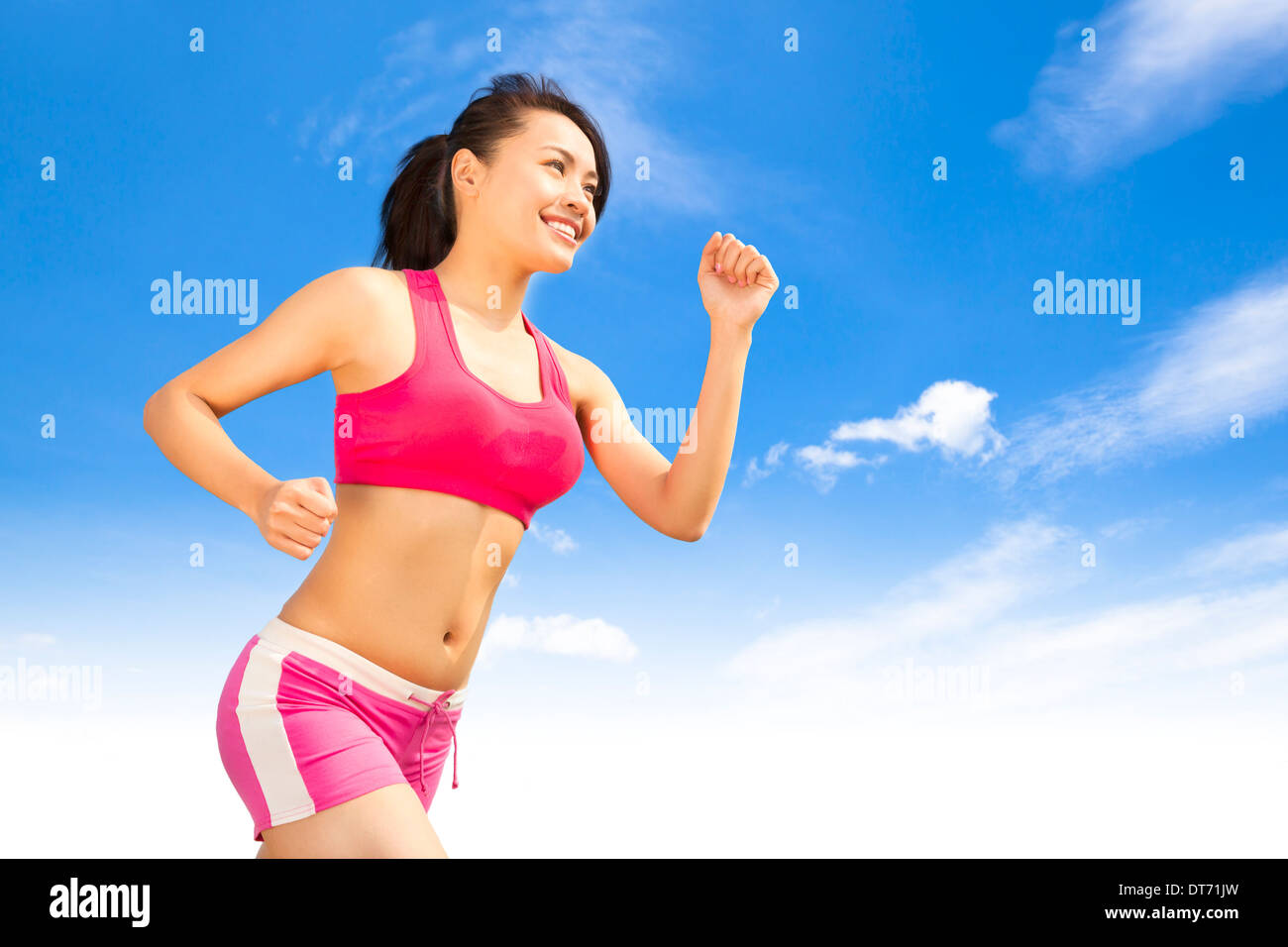 Asian sorridente runner donna jogging nella giornata di sole Foto Stock