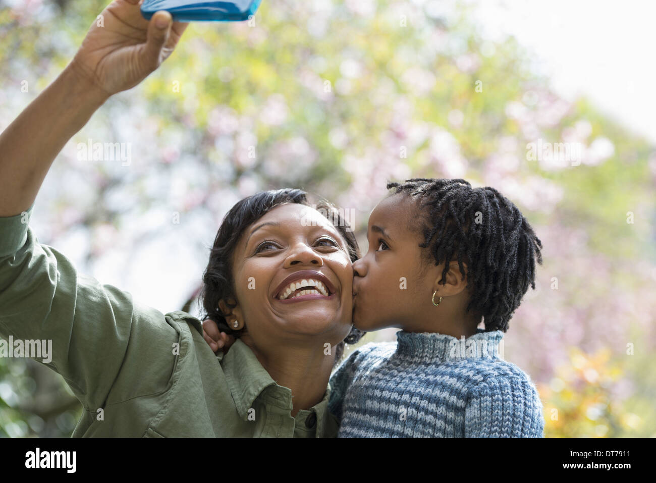 A New York City Park in primavera. Sole fiore di ciliegio. Una madre figlio che posano per una foto scattata con un telefono intelligente. Foto Stock