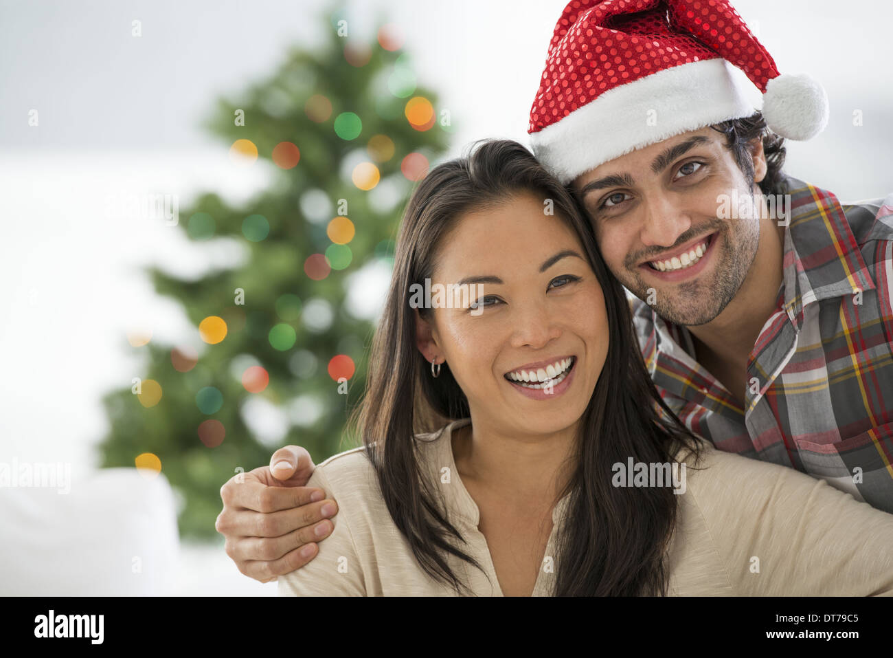 Un uomo in un Babbo Natale hat. A casa. Un albero di Natale decorato. Foto Stock