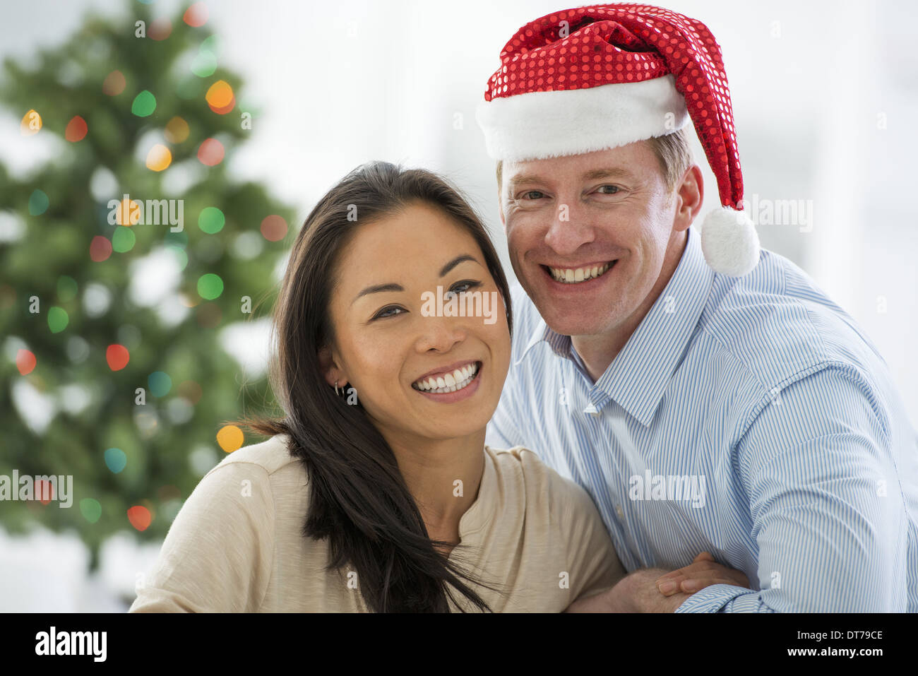 Un uomo in un Babbo Natale hat. A casa. Un albero di Natale decorato. Foto Stock