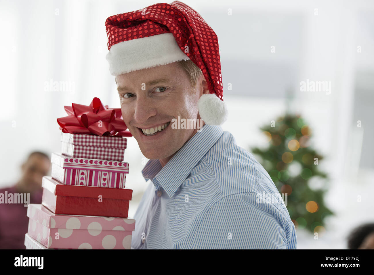 Un uomo in un Babbo Natale hat. A casa. Un albero di Natale decorato. Foto Stock