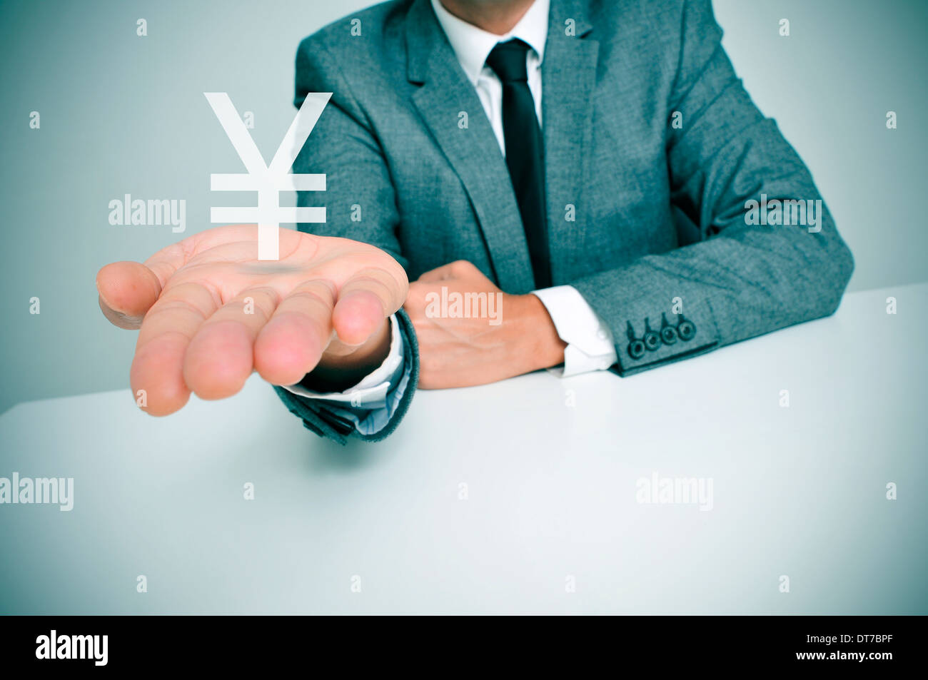 Un imprenditore seduti ad una scrivania che mostra un yuan cinese o giapponese yen segno in mano Foto Stock