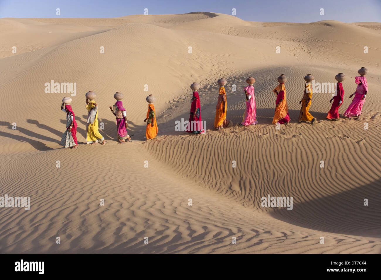 Rajasthan in India deserto di Thar trekking fino al lato di una sabbia dunewomen trasportanti grandi vasi d'acqua equilibrato sulle loro teste Foto Stock