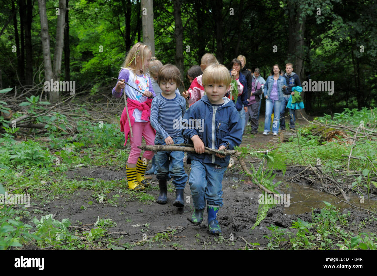 Un gruppo di bambini passeggiate attraverso un bosco insieme con i loro genitori. Foto Stock