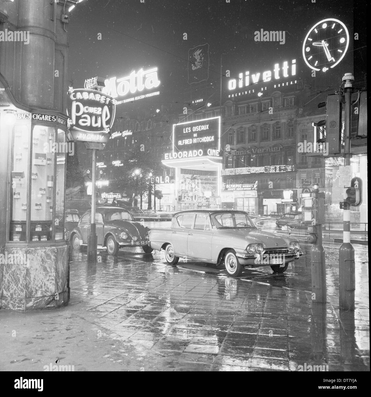 Foto storiche da anni cinquanta che mostra una strada bagnata, serata Bruxelles, Belgio, illuminata da pannelli pubblicitari e segni. Foto Stock