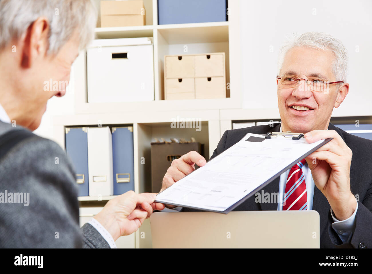 Consulente mostra minuti di consultazione per il cliente per una firma Foto Stock