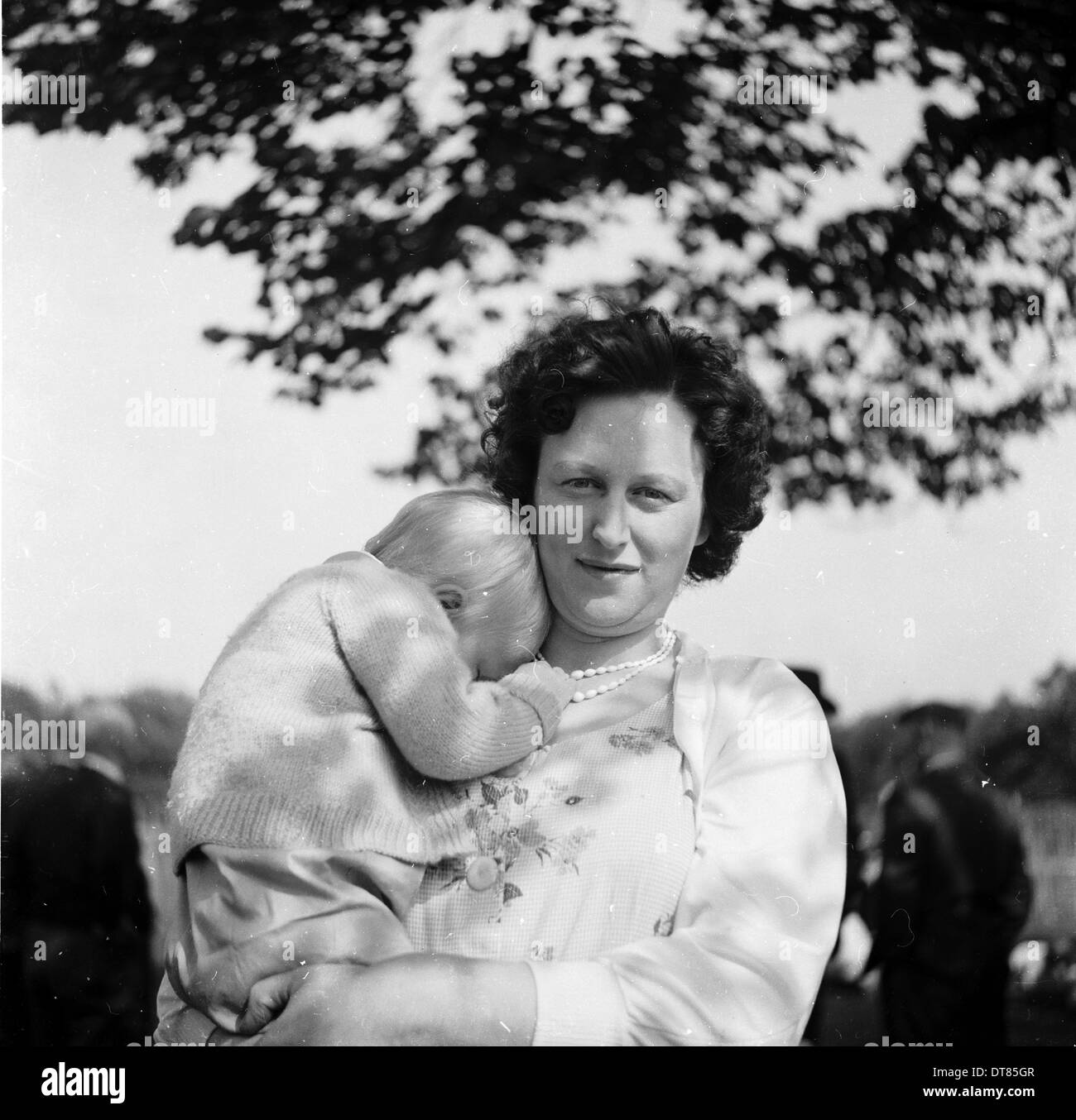 Foto storiche da anni cinquanta che mostra una madre con un bambino sulla sua spalla, Foto Stock