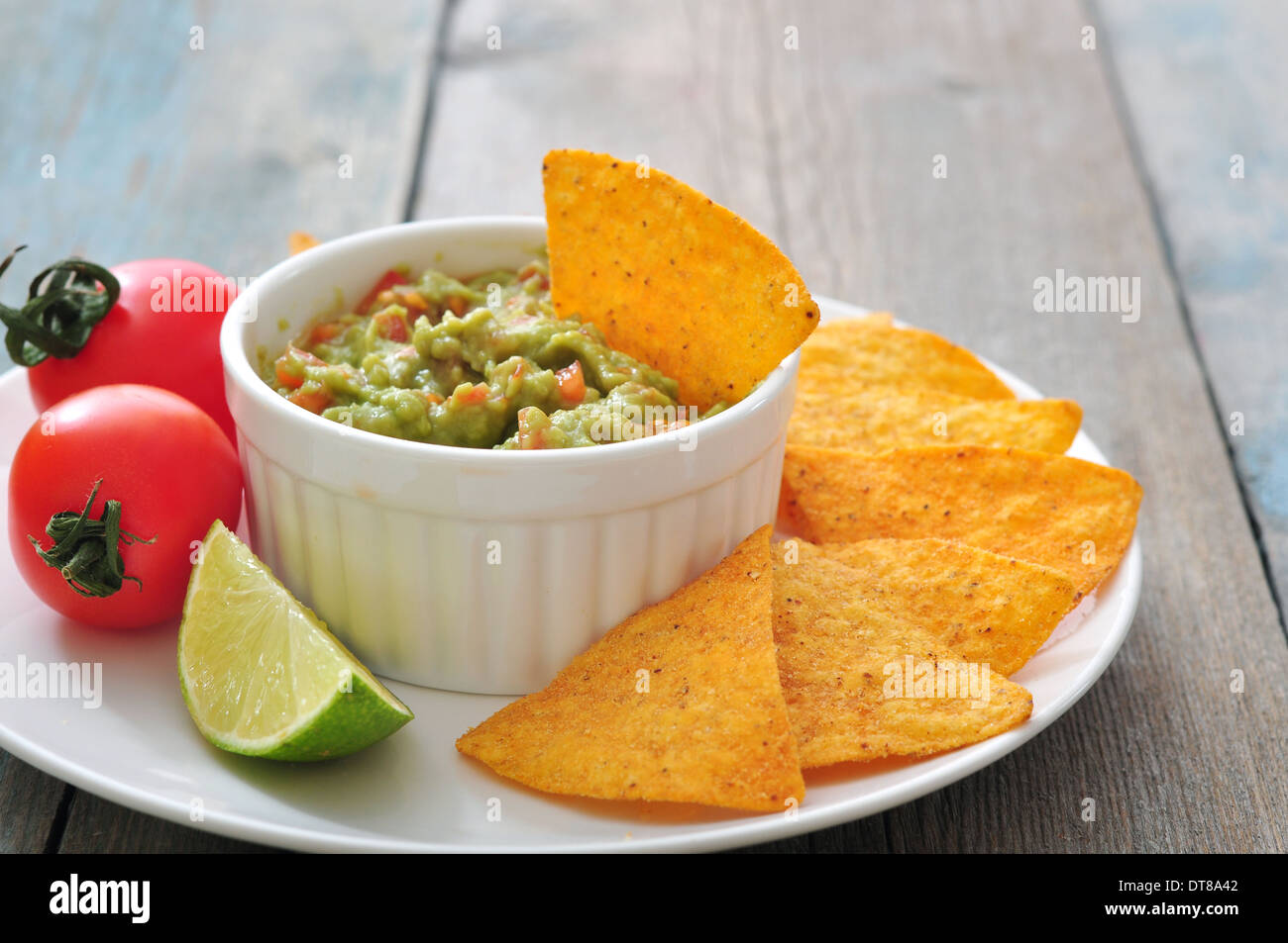 Messicana salsa guacamole con nachos e pomodoro su sfondo di legno Foto Stock