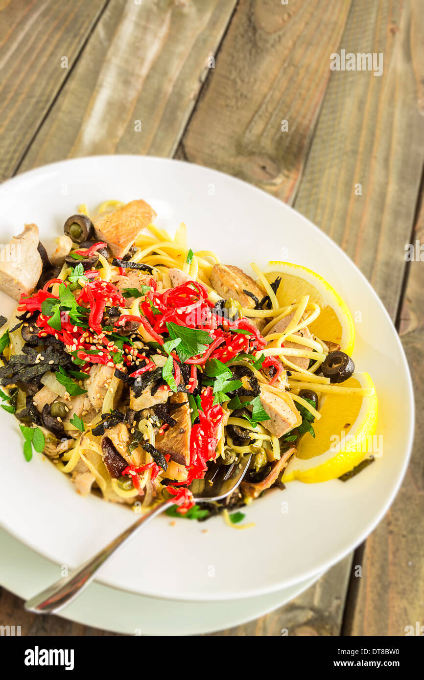 Linguine con tonno ahi e rabboccato con zenzero sott'aceto, olive nere, i semi di sesamo, prezzemolo, nori e basilico, servito con spicchi di limone Foto Stock
