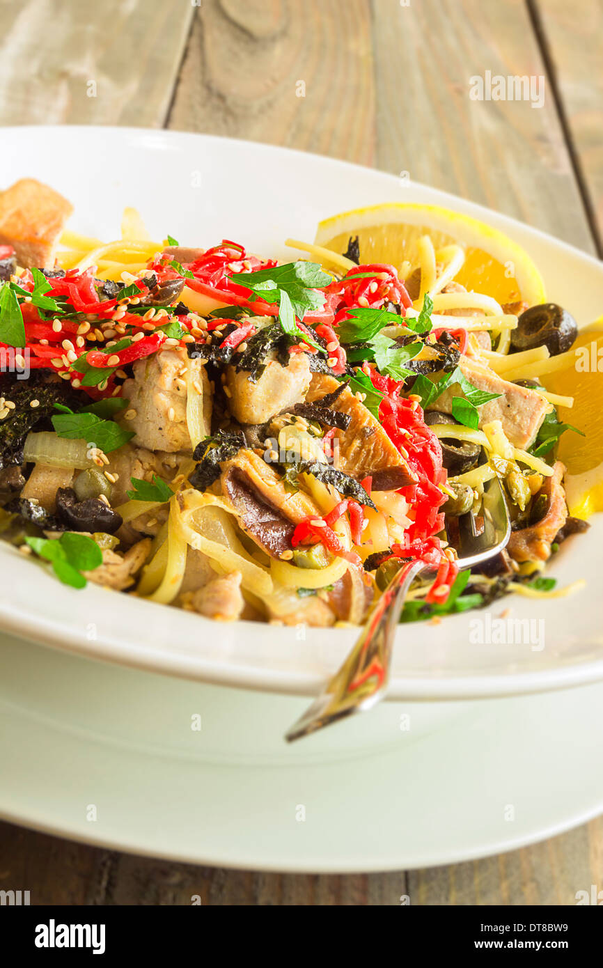 Linguine con tonno ahi e rabboccato con zenzero sott'aceto, olive nere, i semi di sesamo, prezzemolo, nori e basilico, servito con spicchi di limone Foto Stock