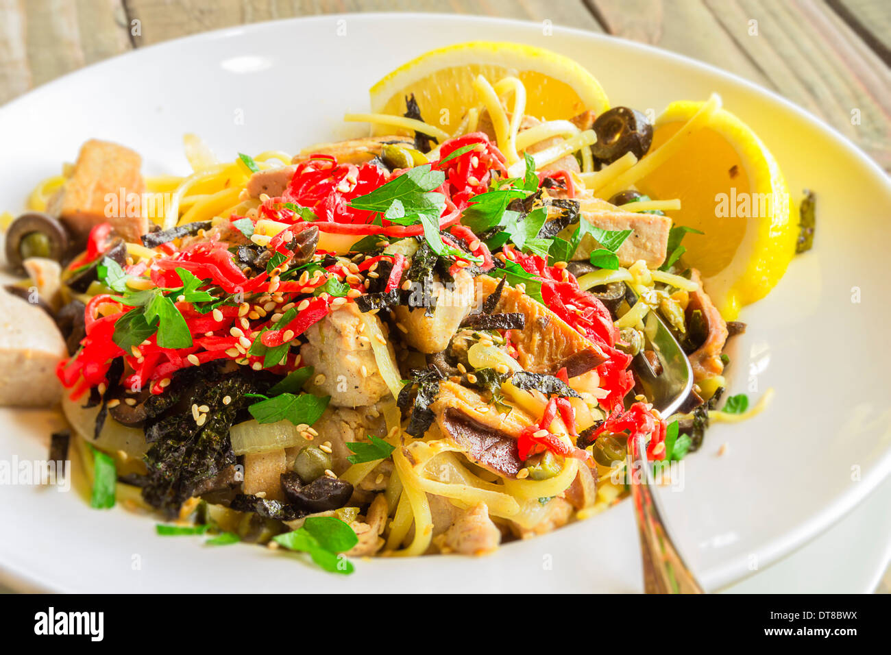 Linguine con tonno ahi e rabboccato con zenzero sott'aceto, olive nere, i semi di sesamo, prezzemolo, nori e basilico, servito con spicchi di limone Foto Stock