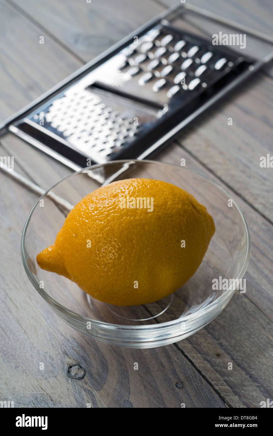 Limone, ciotola e grattugia su una tavola di legno. Messa a fuoco selettiva oltre Limone Foto Stock