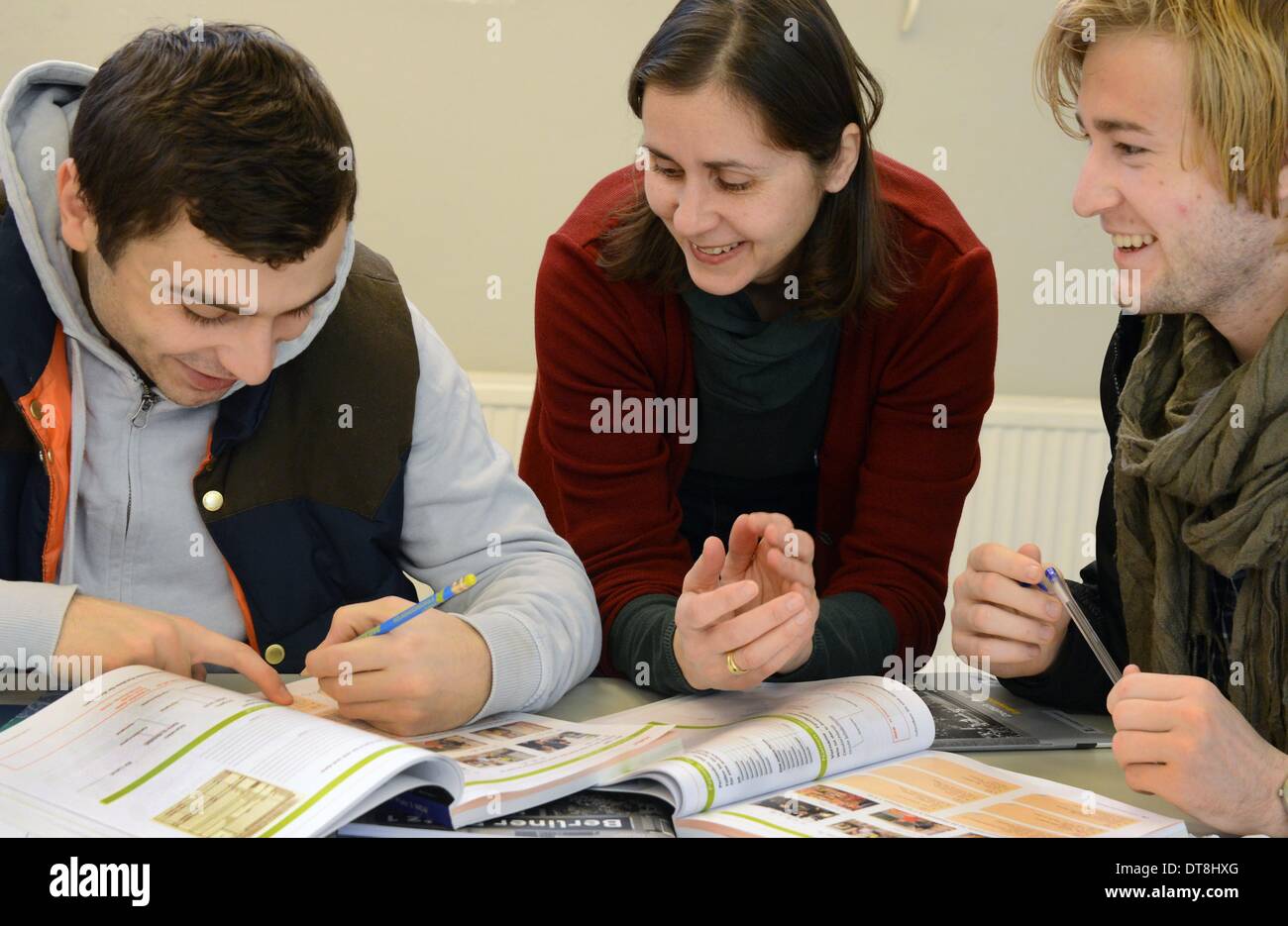 Leipzig, Germania. 28 gen 2014. Due uomini in Afghanistan e Georgia pratica comune saluti tedeschi con il loro insegnante Nadja Wollscheid durante un corso di integrazione per gli immigrati presso l'adulto di alta scuola in Leipzig, Germania, 28 gennaio 2014. Foto: Waltraud Grubitzsch/dpa/Alamy Live News Foto Stock