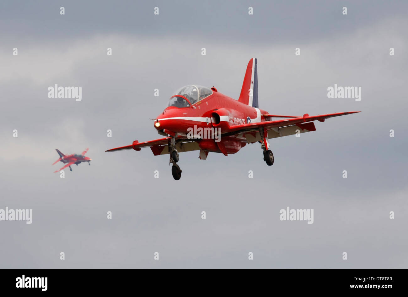 RAF freccia rossa di atterraggio su pista con la freccia rossa in background banking per approccio dietro di esso. Le frecce rosse Hawk aeromobili. Foto Stock