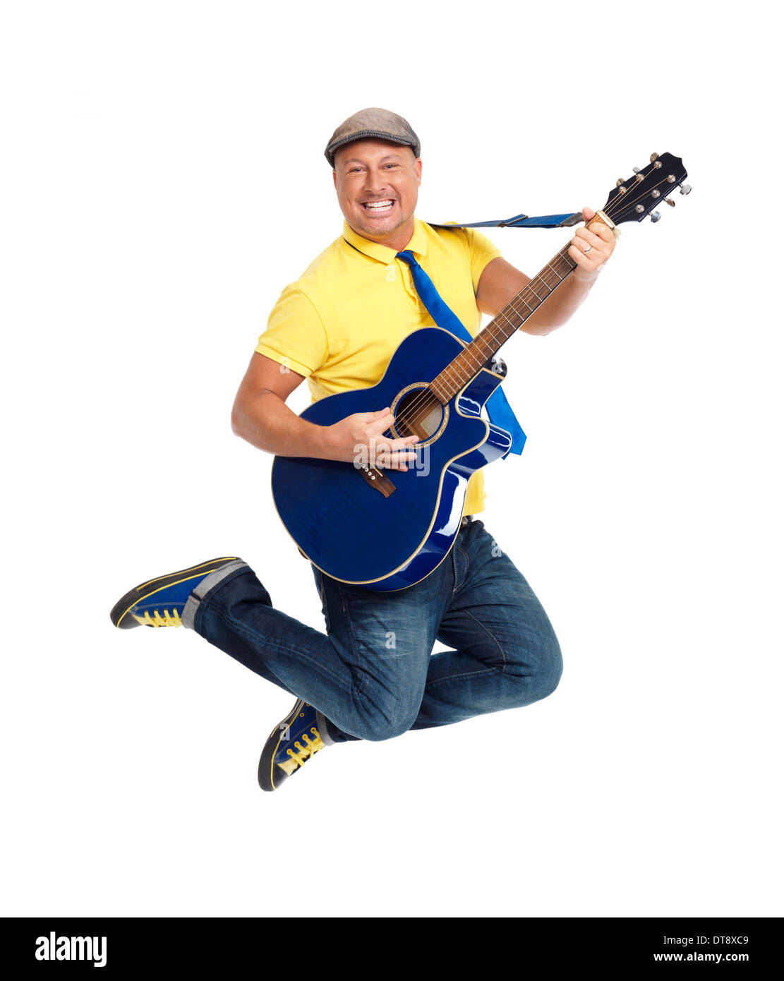 Sorridenti giovane chitarrista jumping con una chitarra acustica in aria isolata su sfondo bianco Foto Stock
