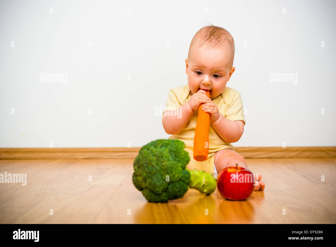 Uno stile di vita sano. Baby mangiare frutta e verdura - al chiuso in casa Foto Stock