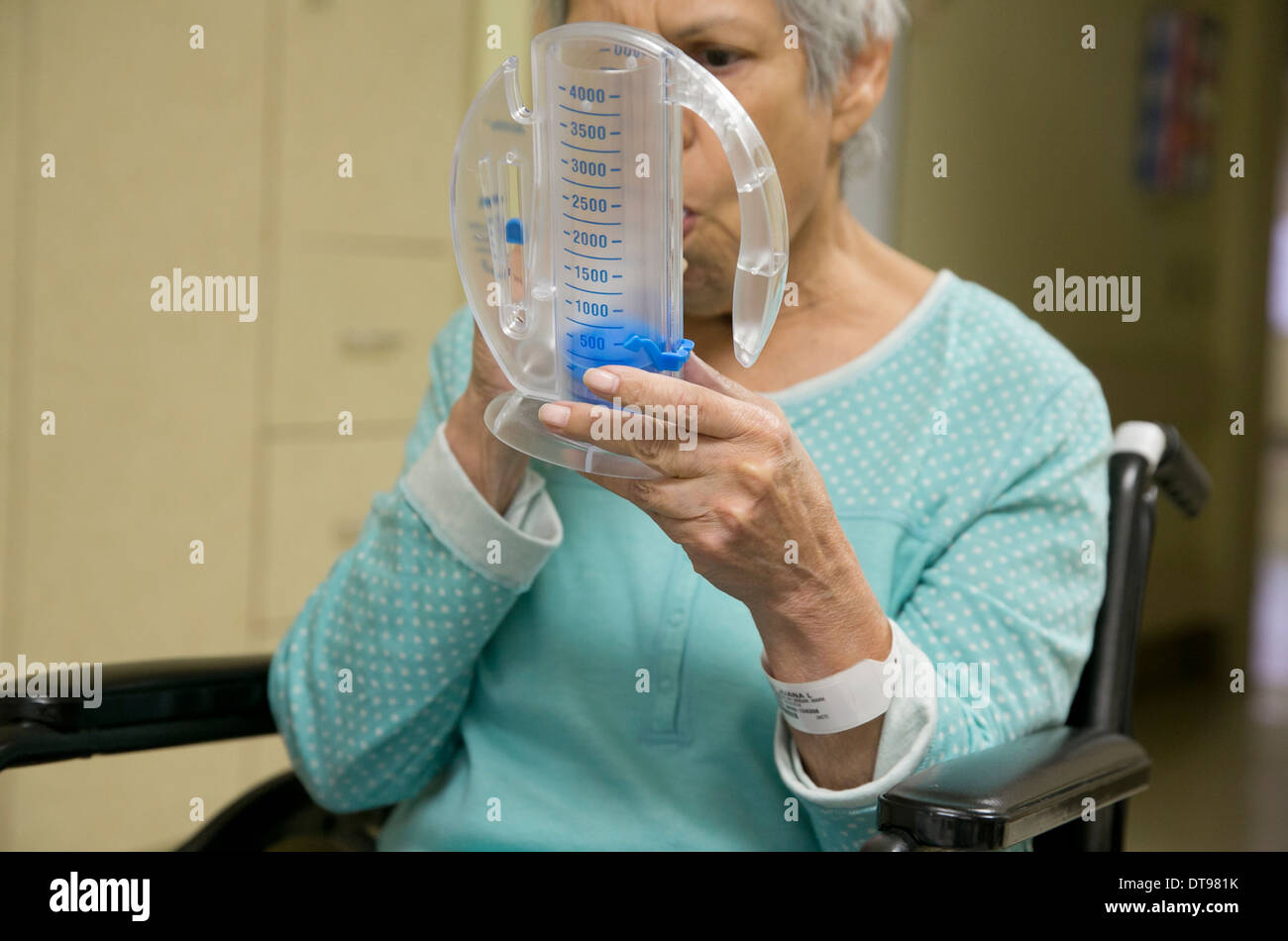 75 enne ispanico senior citizen utilizza un medico di esercizio di respirazione apparecchio mentre in un ospedale di riabilitazione in Texas. Foto Stock