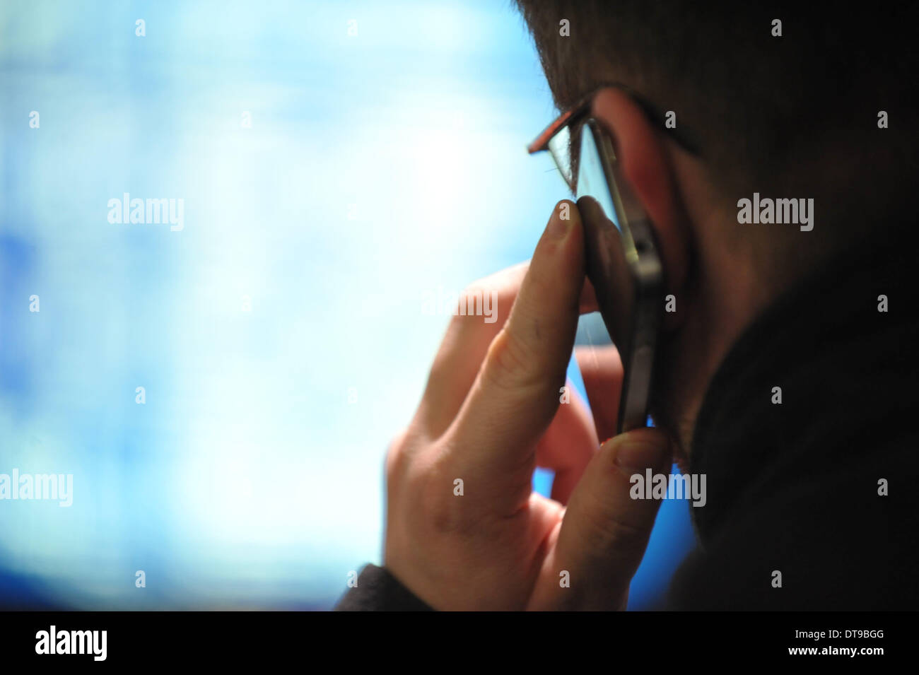 MANCHESTER, REGNO UNITO. 12 Febbraio, 2014. Un uomo chat sul suo telefono cellulare dopo aver appreso che i venti forti in tutto il Regno Unito hanno portato a interruzioni di viaggio la sera per pendolari alla stazione dei treni di Manchester Piccadilly. Alcuni viaggiatori hanno consigliato di rimandare i loro piani di viaggio fino al giorno successivo. Credito: Russell Hart/Alamy Live News. Foto Stock