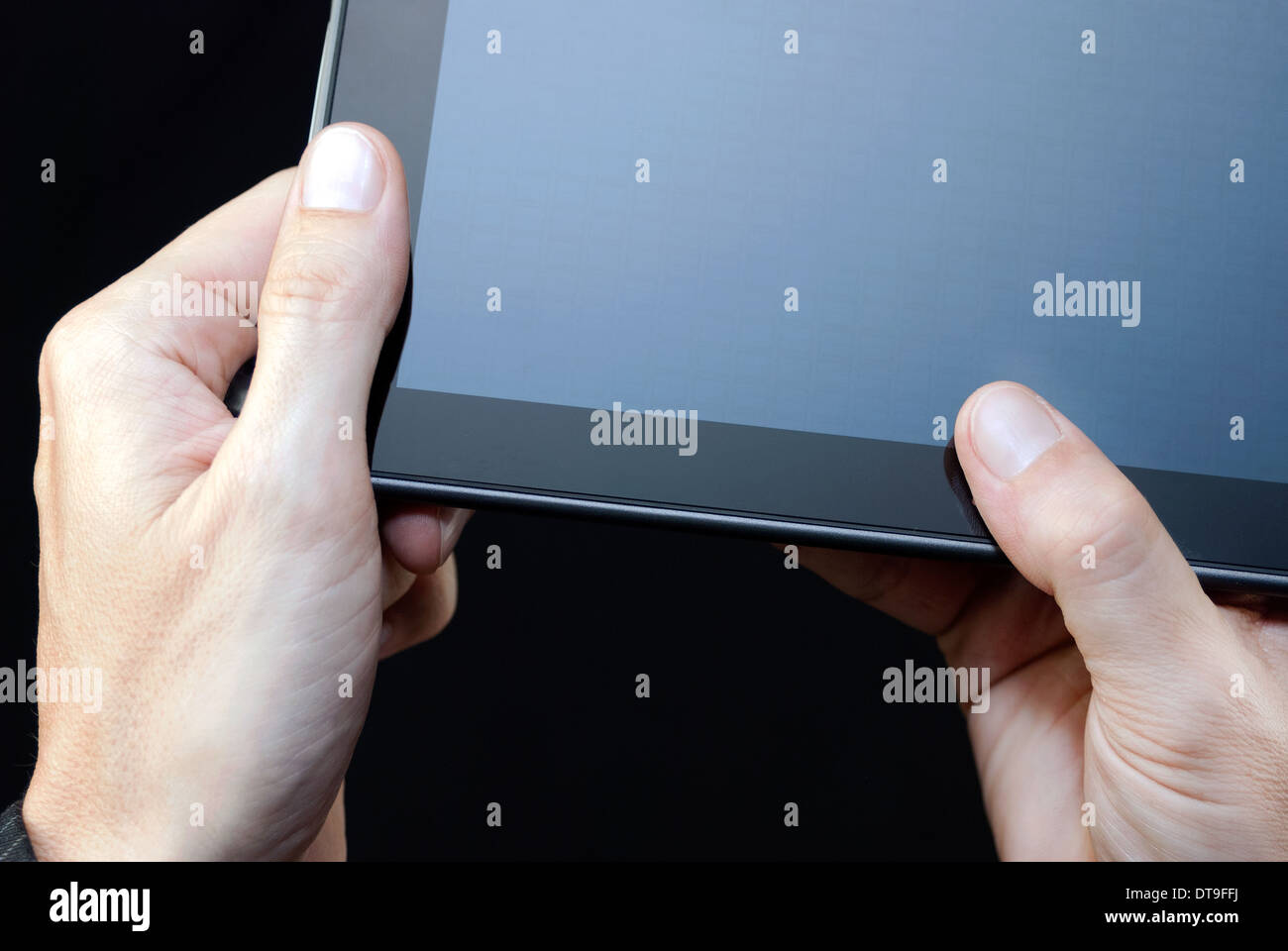 Close-up di una mano che tiene un tablet non illuminato, in alto a destra. Foto Stock