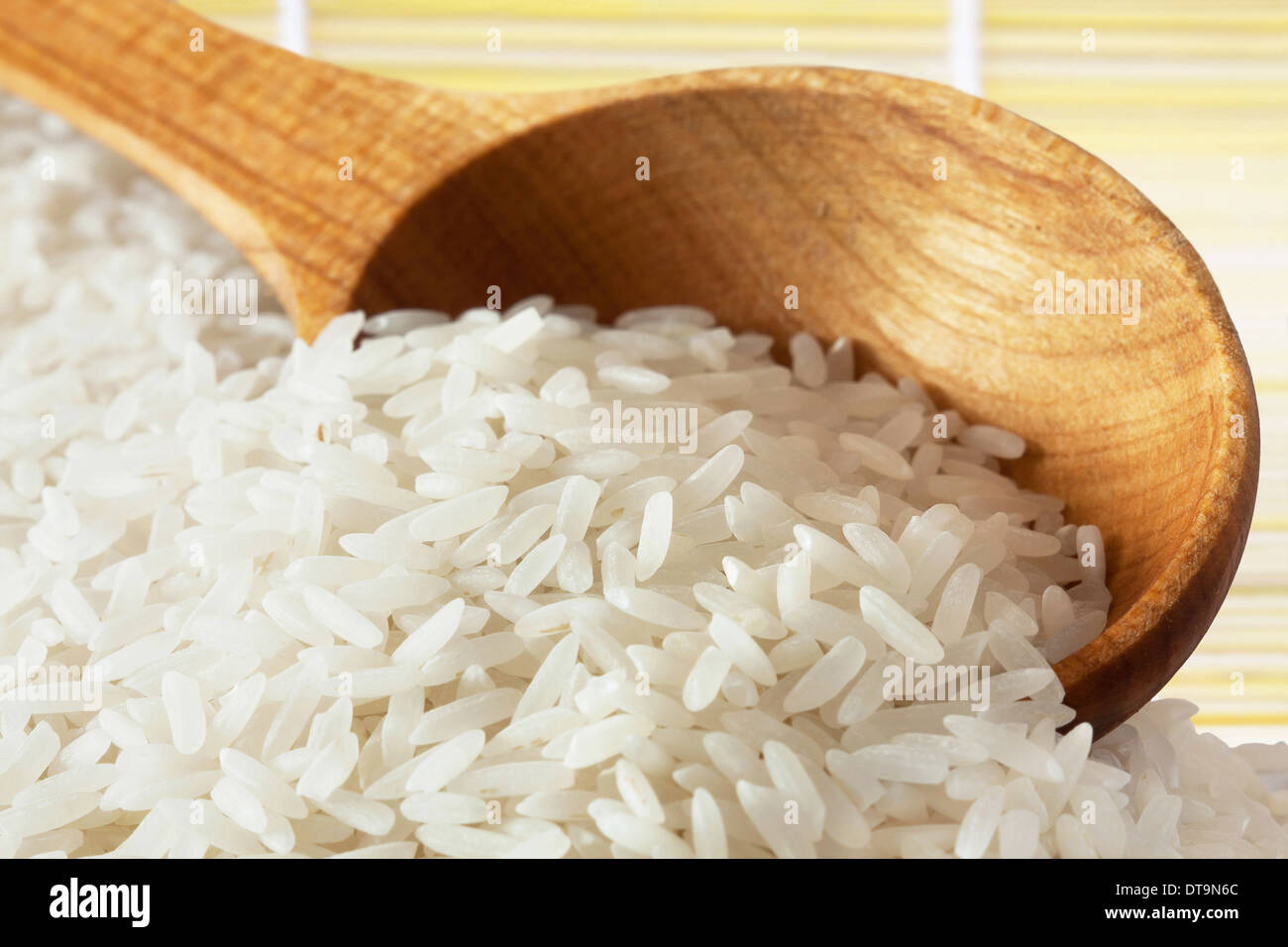 Bianco lungo il riso crudo sul cucchiaio di legno Foto Stock
