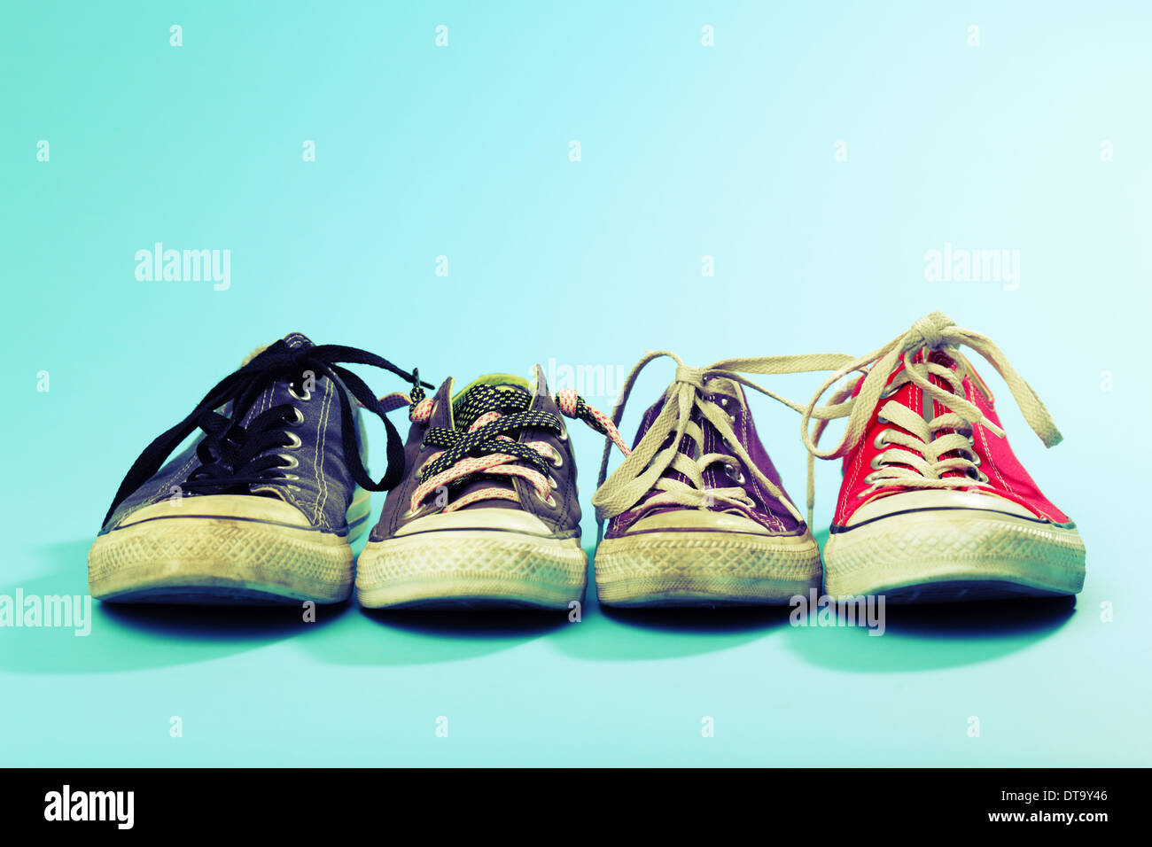 Una linea di Converse scarpe di diverse dimensioni e colori sparato contro  uno sfondo blu. Croce trasformati. Studio shot Foto stock - Alamy