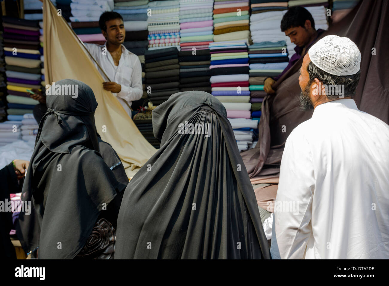 Due donne musulmane e un uomo di acquistare il materiale al mercato Mangaldas, Mumbai, Maharashtra, India Foto Stock