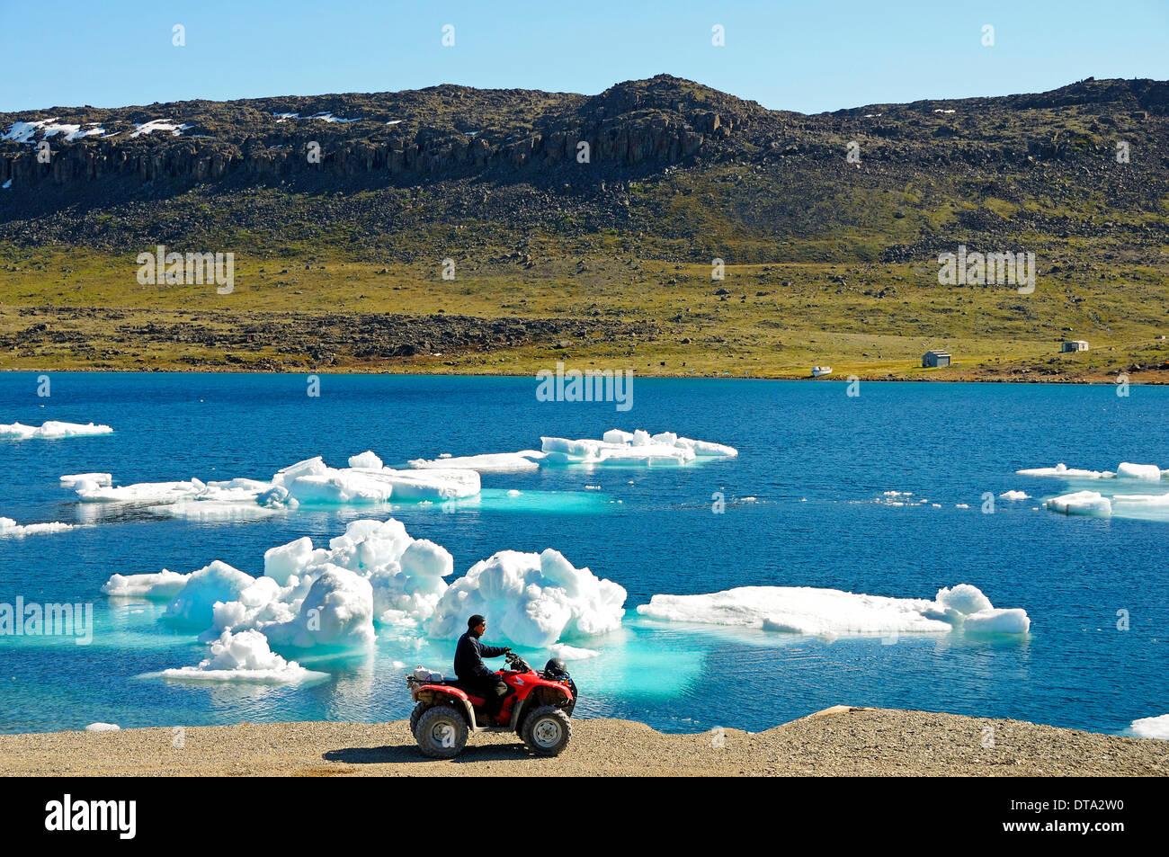 Uomo di popolazioni Inuit in sella a una moto quad, ATM, parcheggiato sulla riva del mare Beaufort, Oceano Artico, Victoria Island Foto Stock