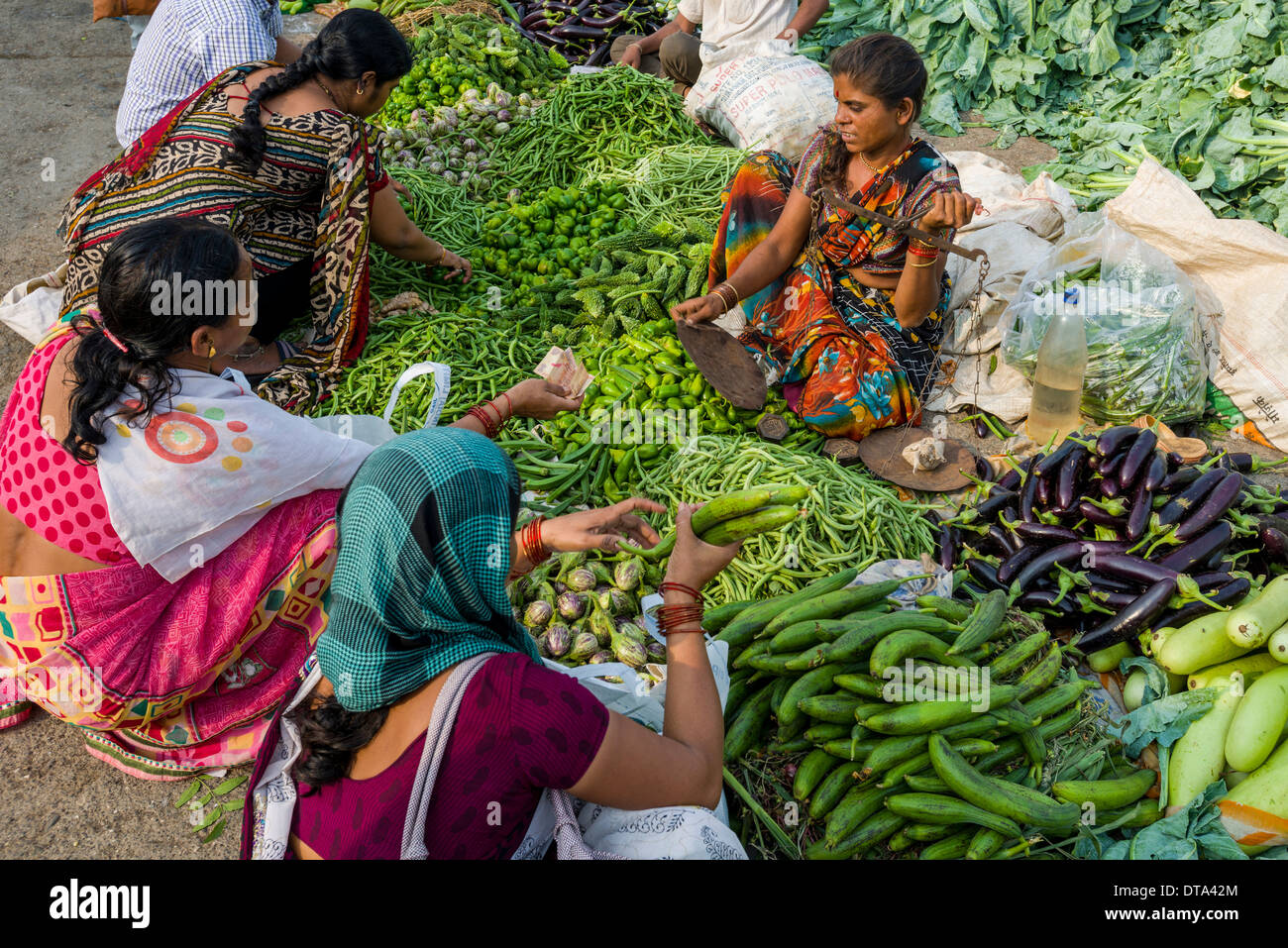 Una donna è la vendita di melanzane, peperoni, i cavolfiori e i cetrioli presso il settimanale mercato ortofrutticolo, Nasik, Maharashtra, India Foto Stock