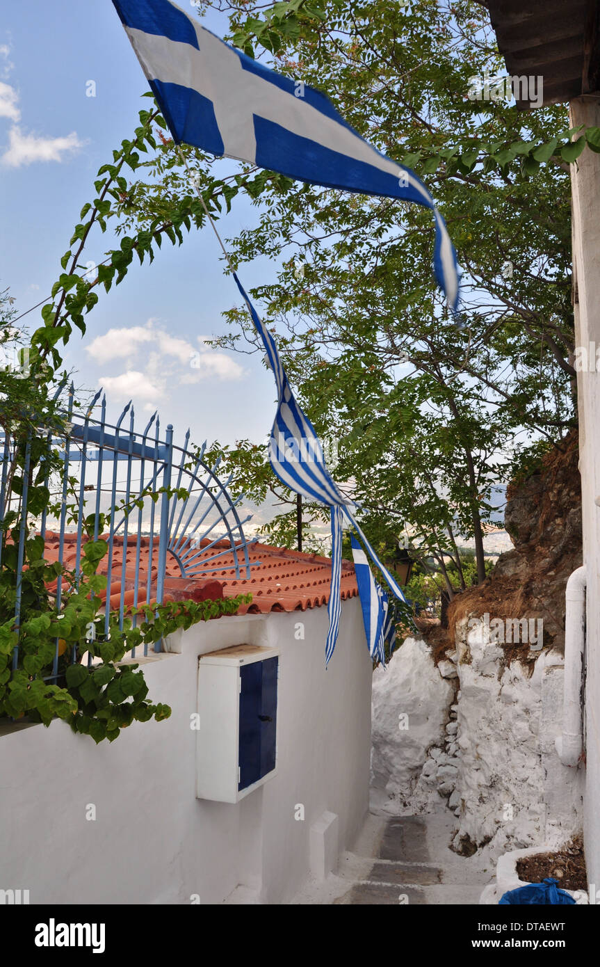 Stretto vicoletto con bandiere Greca e la piccola casa nel tradizionale quartiere di Anafiotika, Atene, Grecia. Foto Stock
