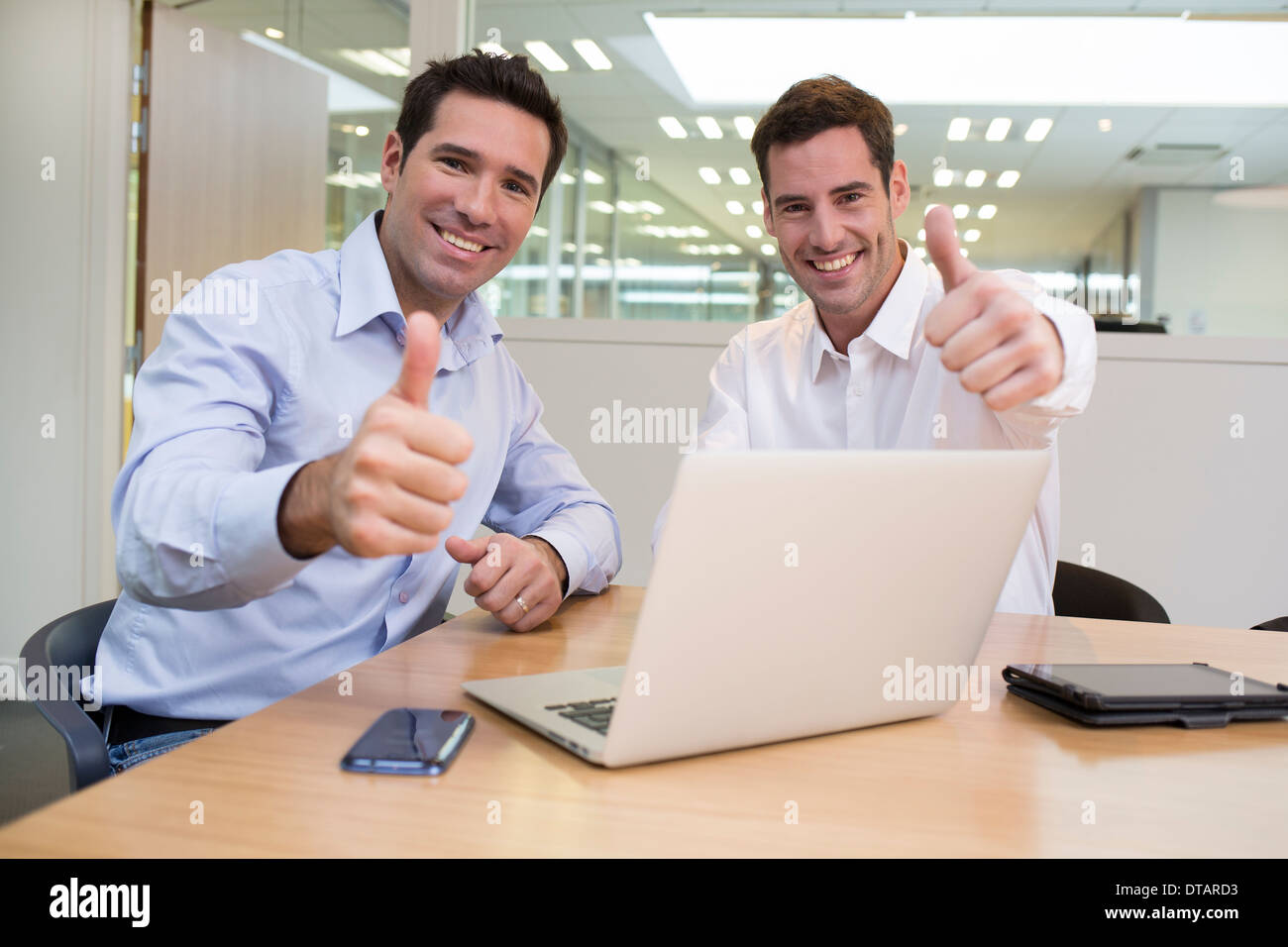 Il successo degli imprenditori sorridente in ufficio, guardando la telecamera, dando pollice in alto Foto Stock