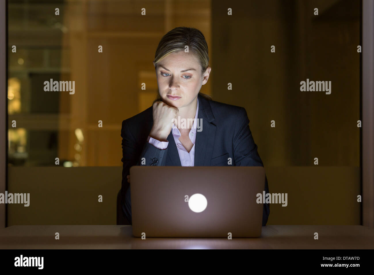 Imprenditrice lavora fino a tardi nel suo ufficio su laptop Foto Stock