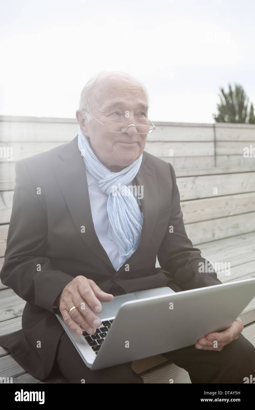 Senior Uomo con laptop, guardando lontano Foto Stock