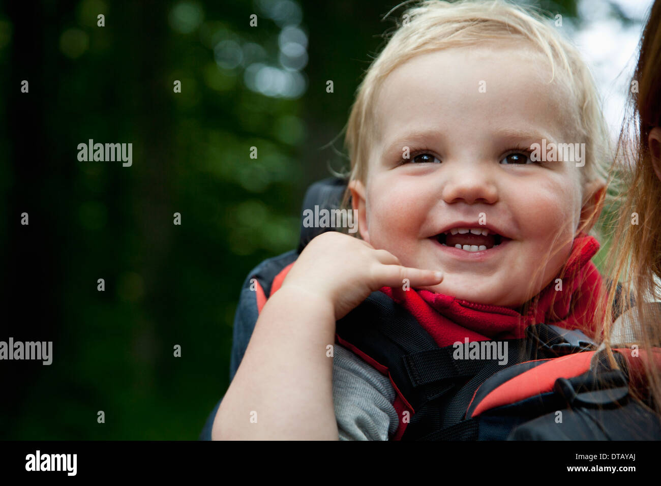 Baby boy in sella a un vettore, piggyback con sua madre, close-up Foto Stock