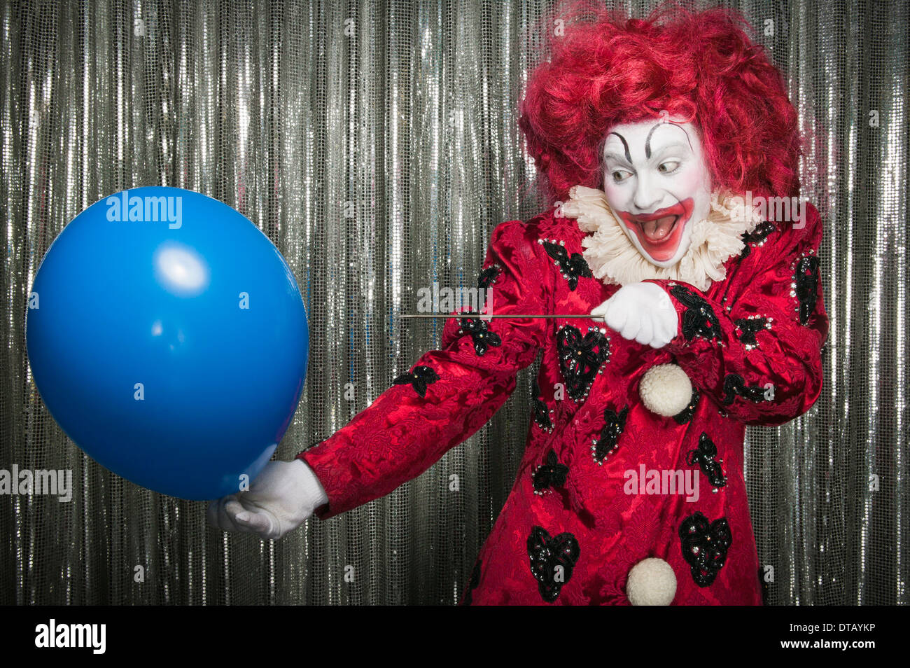 Un clown prepararsi al pop di un palloncino con un ago Foto Stock