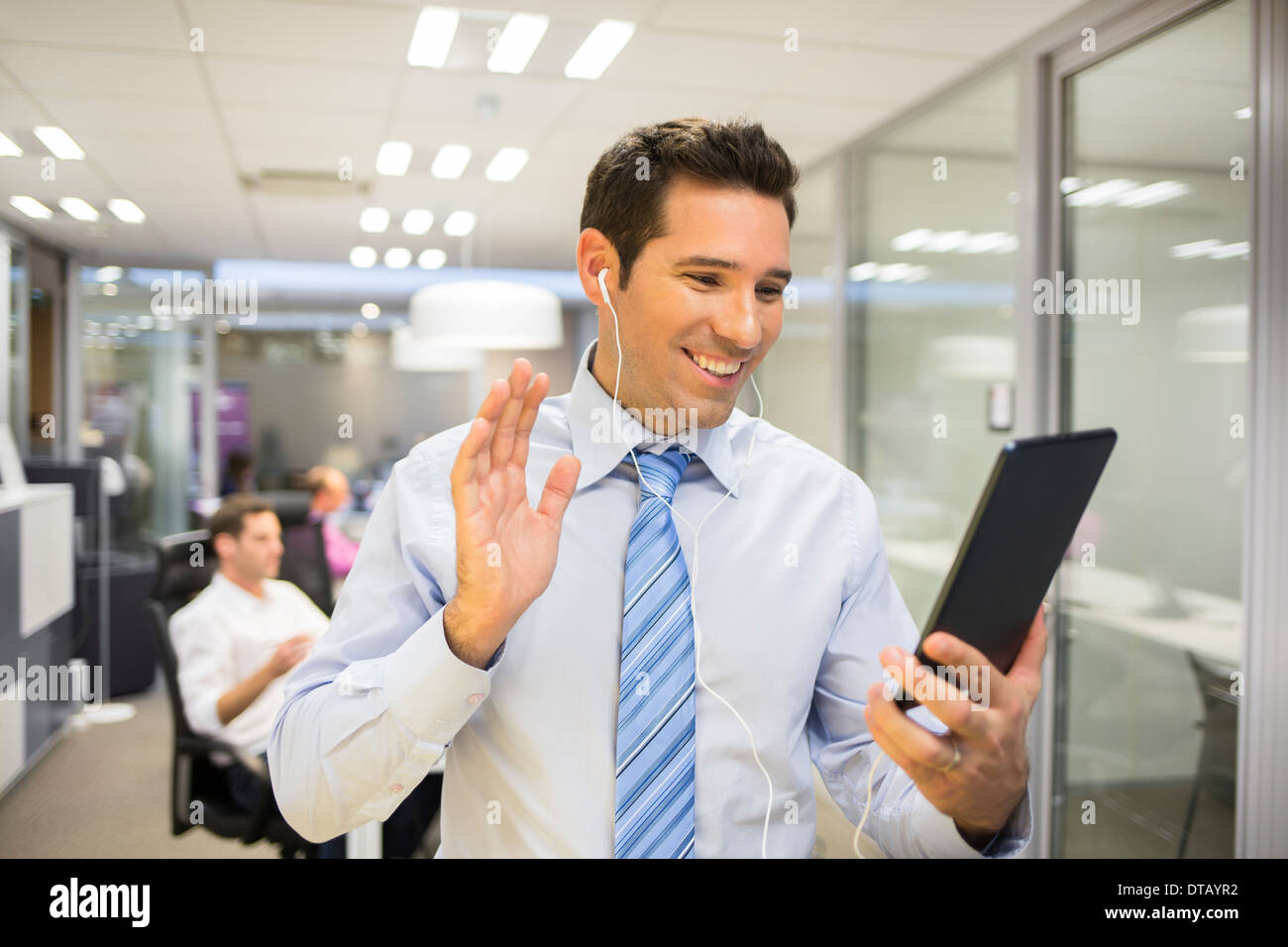 Imprenditore sorridente in chat su internet con Tablet Pc, sullo sfondo di office Foto Stock