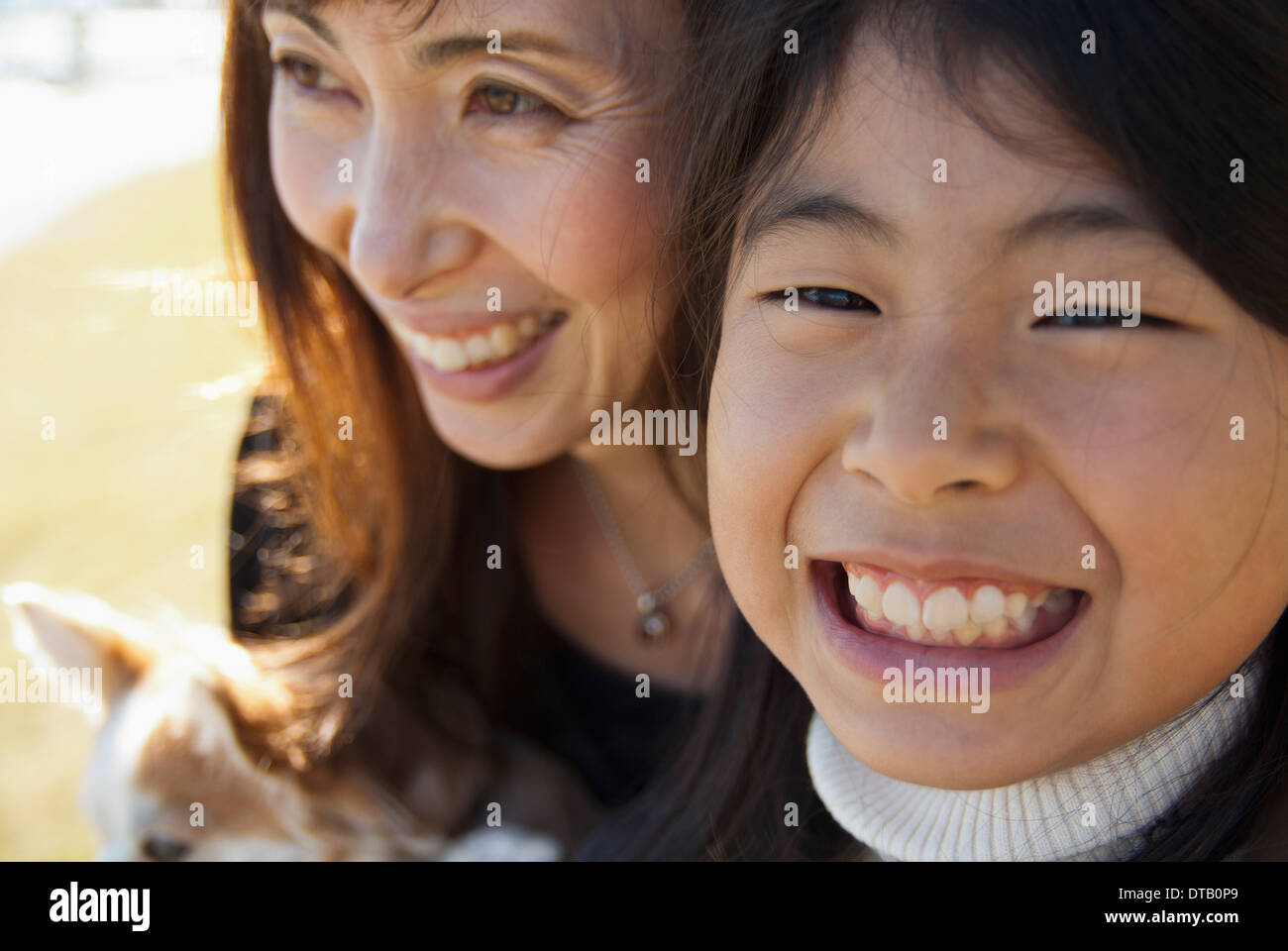 Un grinning madre e figlia con il cane, close-up Foto Stock