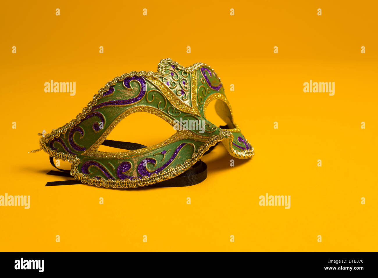 Verde, oro, porpora Mardi Gras mask su un brillante sfondo giallo Foto Stock