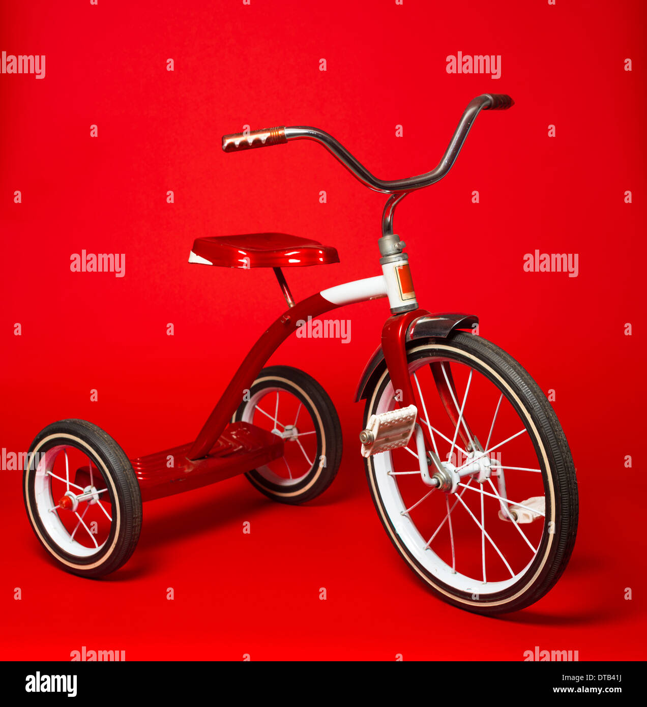 Un vintage red triciclo su un brillante sfondo rosso Foto Stock