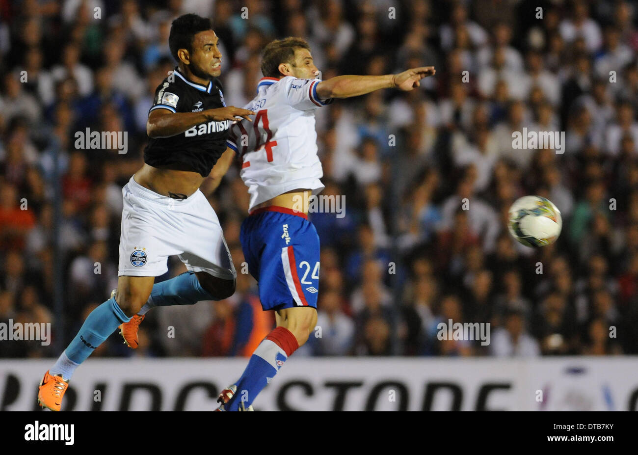 Montevideo, Uruguay. Xiii Febbraio, 2014. Nacional's Ivan Alonso (R), il sistema VIES per la palla con il Gremio's Werley Anania (L), durante la loro Copa Libertadores soccer match, tenutasi al Gran Parque Central Stadium, a Montevideo, Uruguay, il 13 febbraio, 2014. © Nicolas Celaya/Xinhua/Alamy Live News Foto Stock