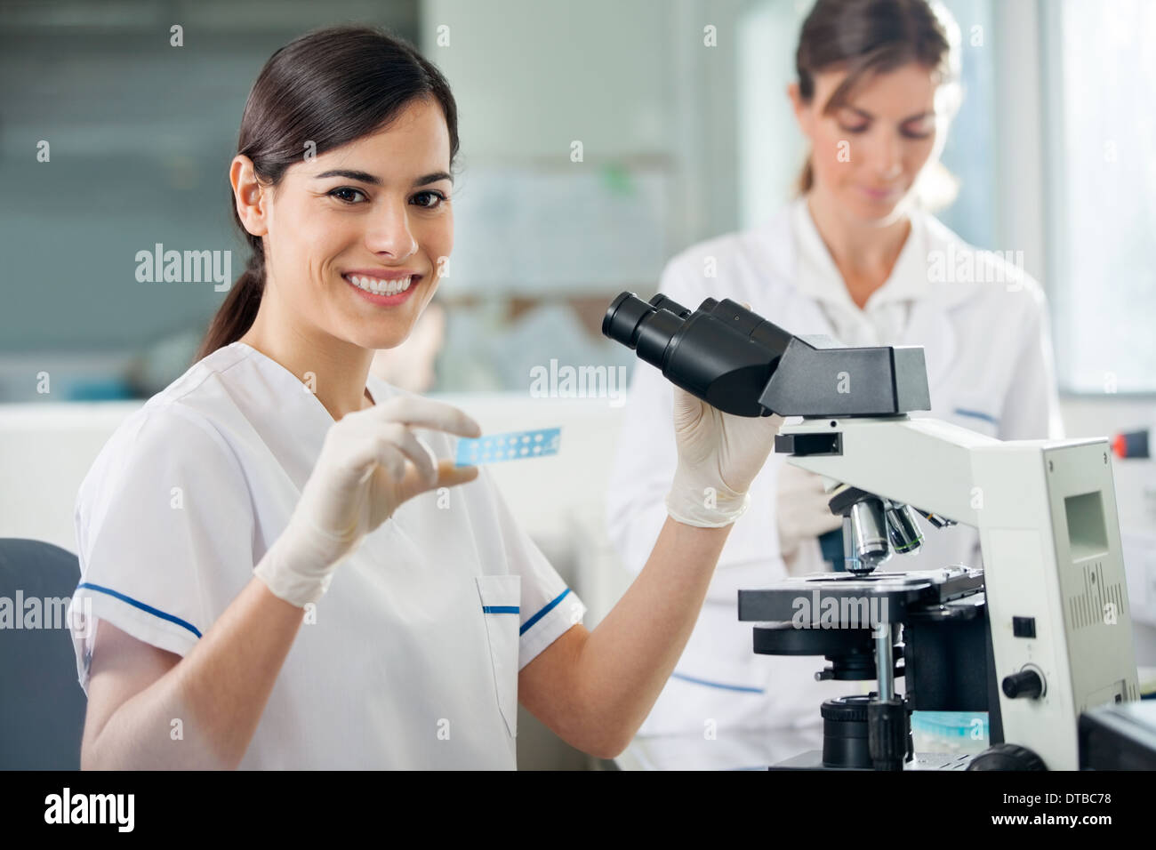 Ricercatore femmina mediante microscopio in laboratorio Foto Stock