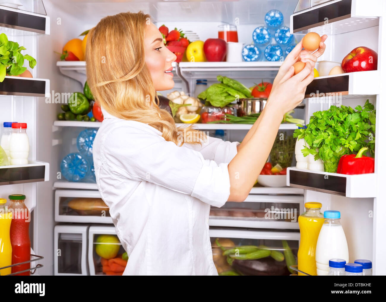 Carino donna prendendo le uova dal frigo, attraente casalinga prendersi cura di salute, freschi e saporiti alimenti biologici, mangiare sano Foto Stock