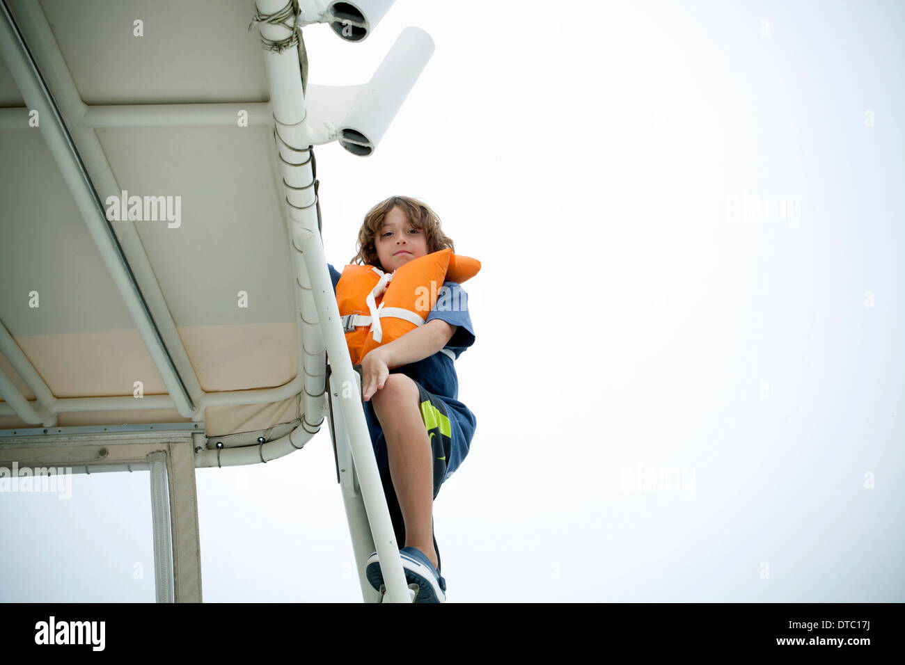 Giovane ragazzo in life jacket salire gradini in barca Foto Stock