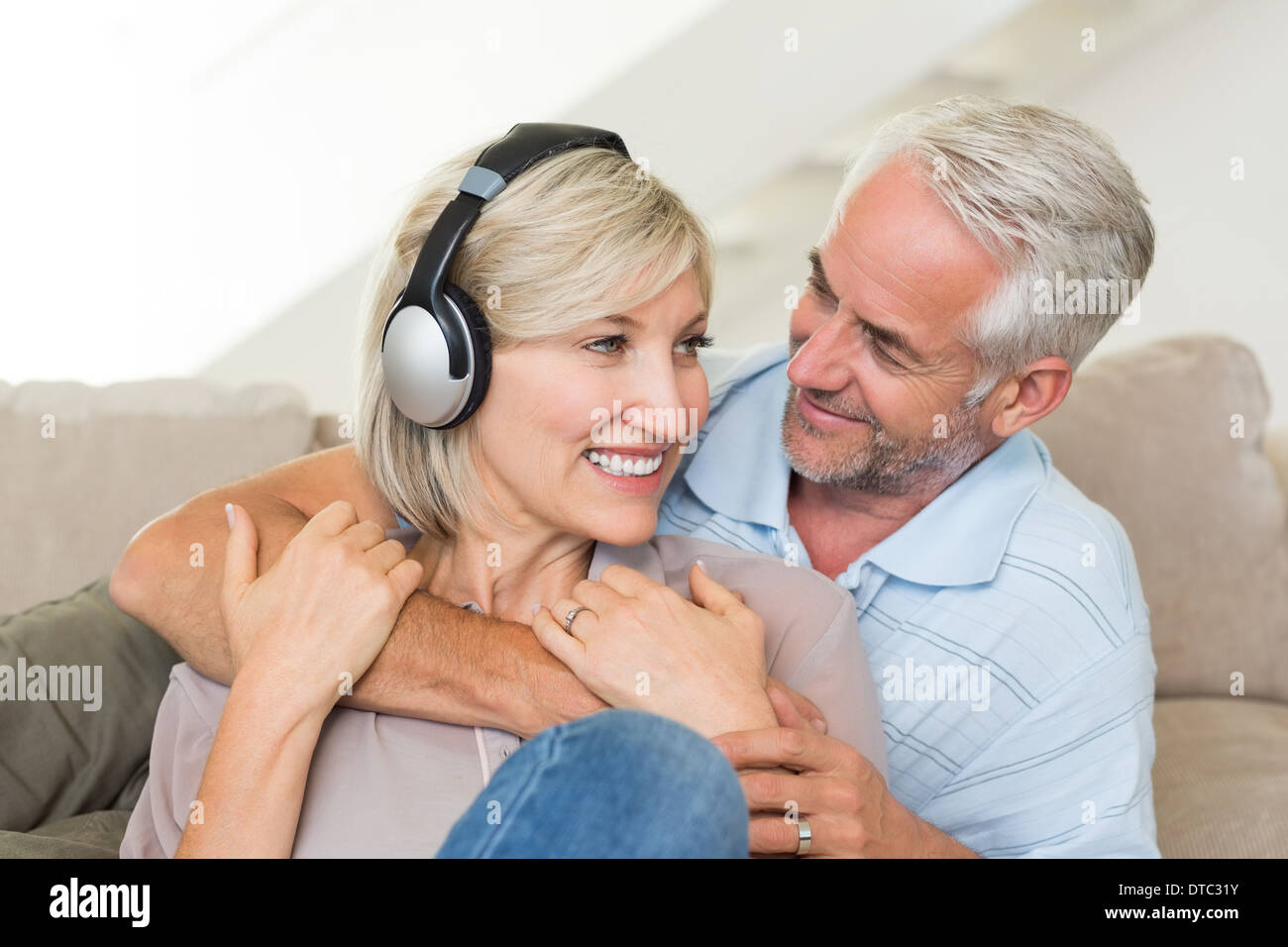 Uomo maturo abbracciando la donna da dietro sul divano Foto Stock