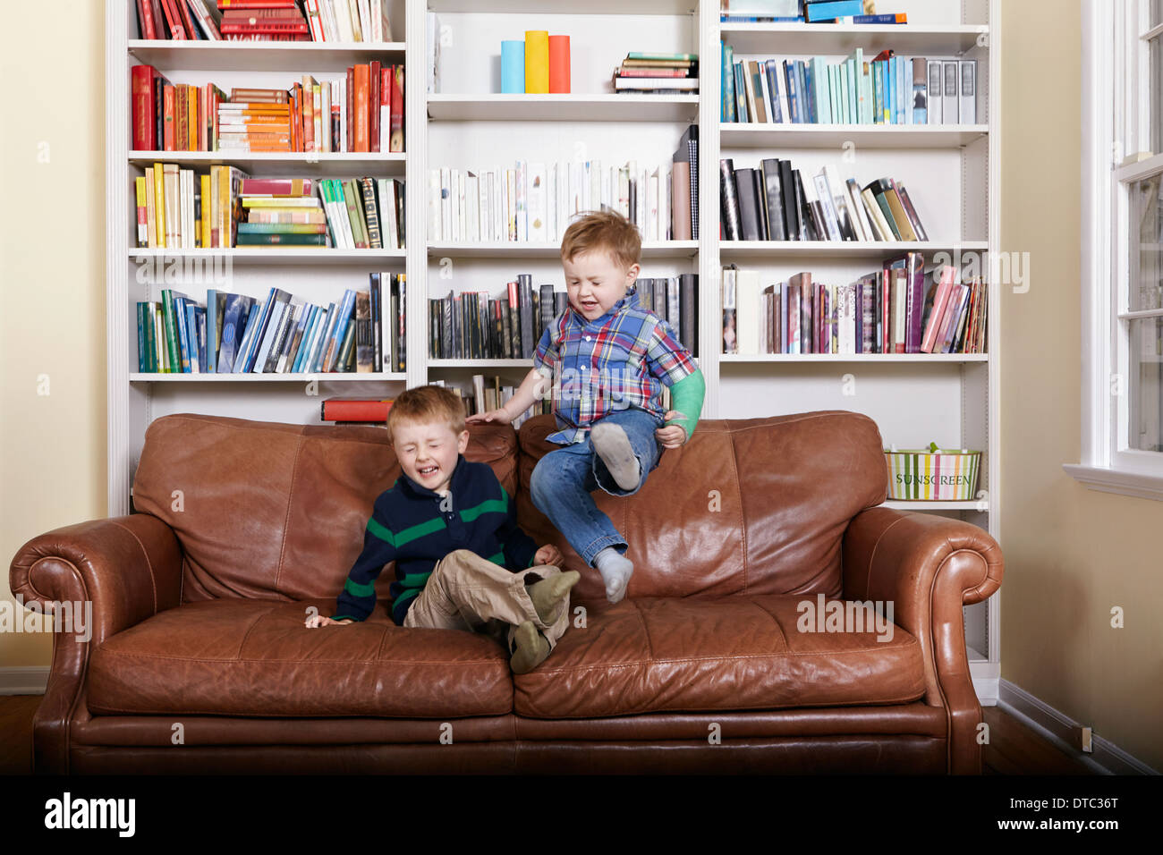Due giovani fratelli di saltare sul divano Foto Stock