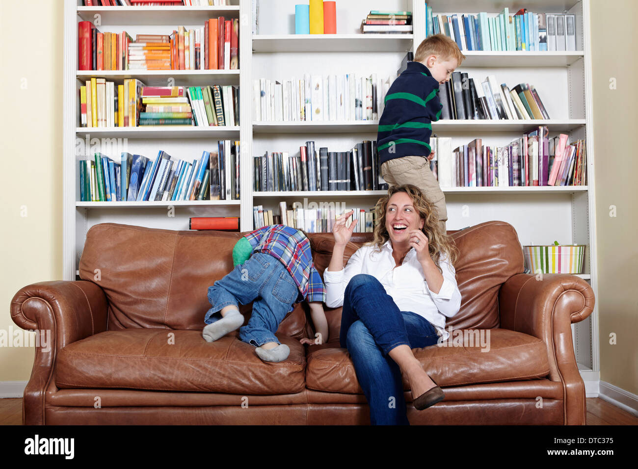Madre e figli giovani giocando sul divano Foto Stock