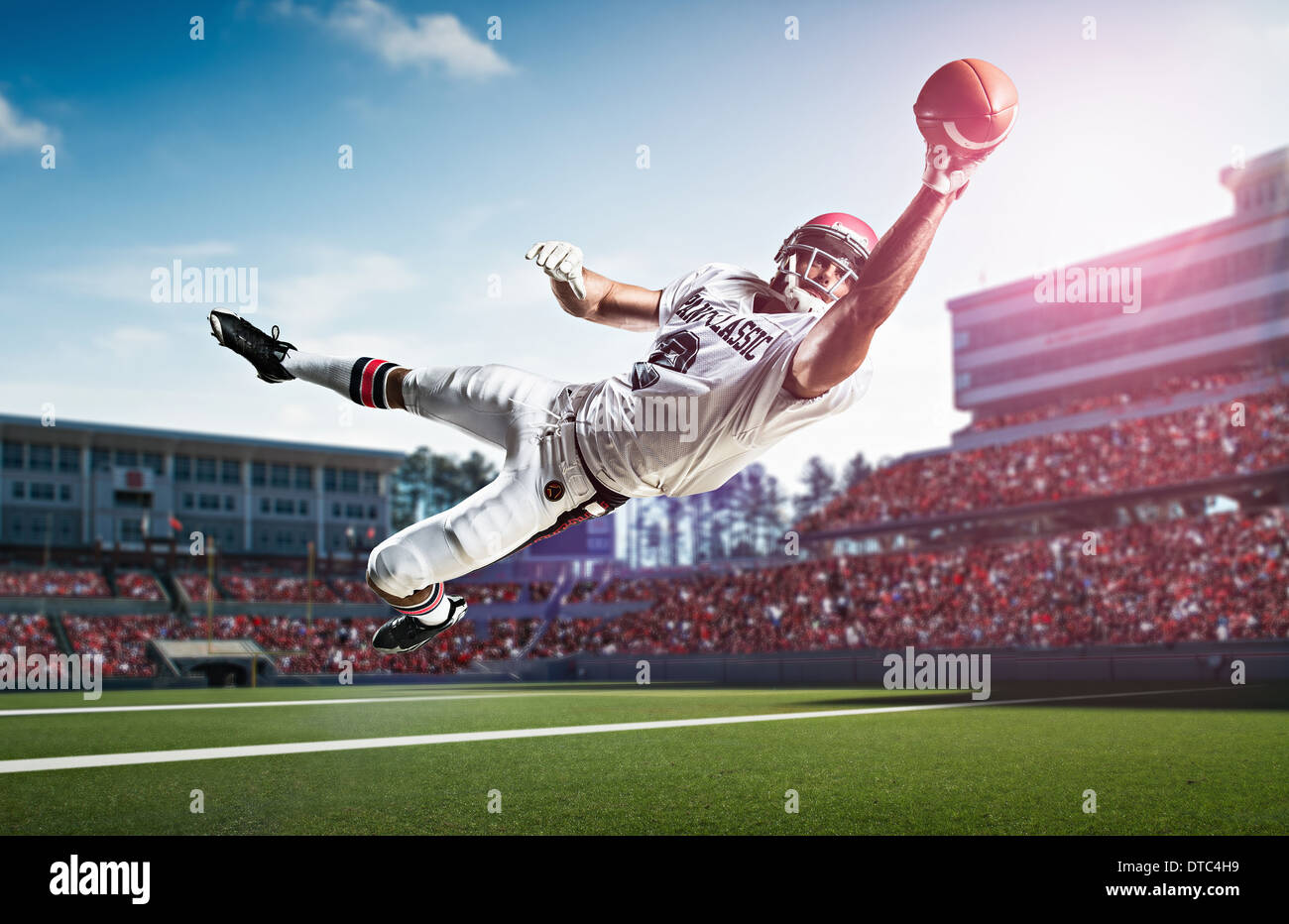 Giocatore di football americano la cattura di sfera metà aria nel Stadium Foto Stock