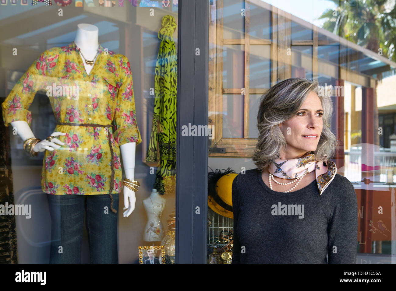 Donna in piedi al di fuori del negozio finestra Foto Stock