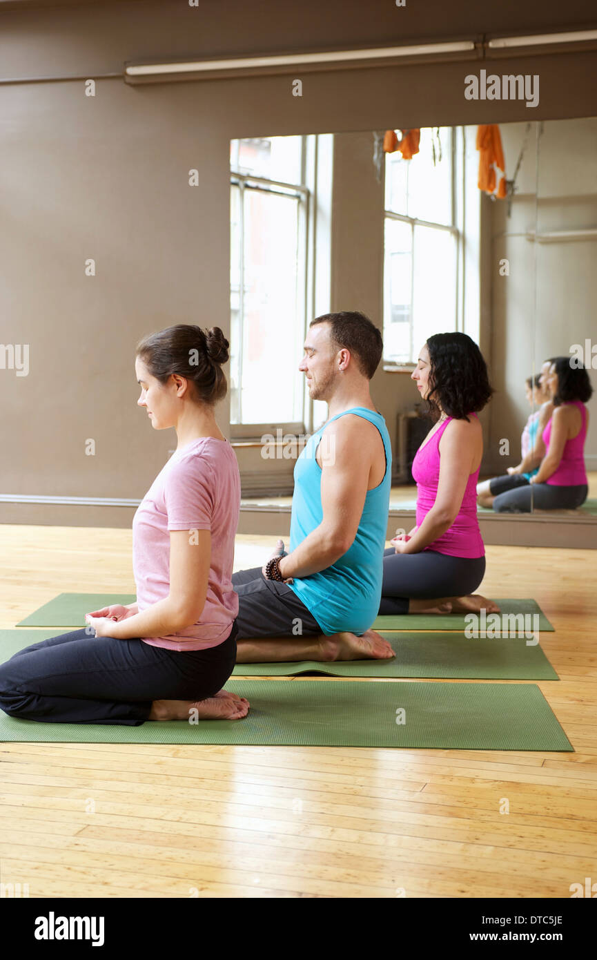 Le persone in ginocchio di yoga classe Foto Stock