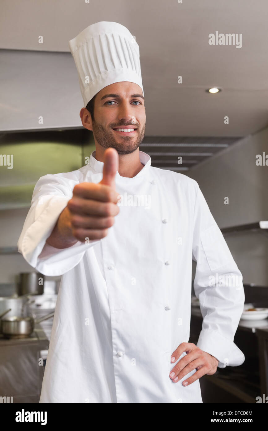 Felice giovane chef guardando la telecamera che mostra il pollice in alto Foto Stock