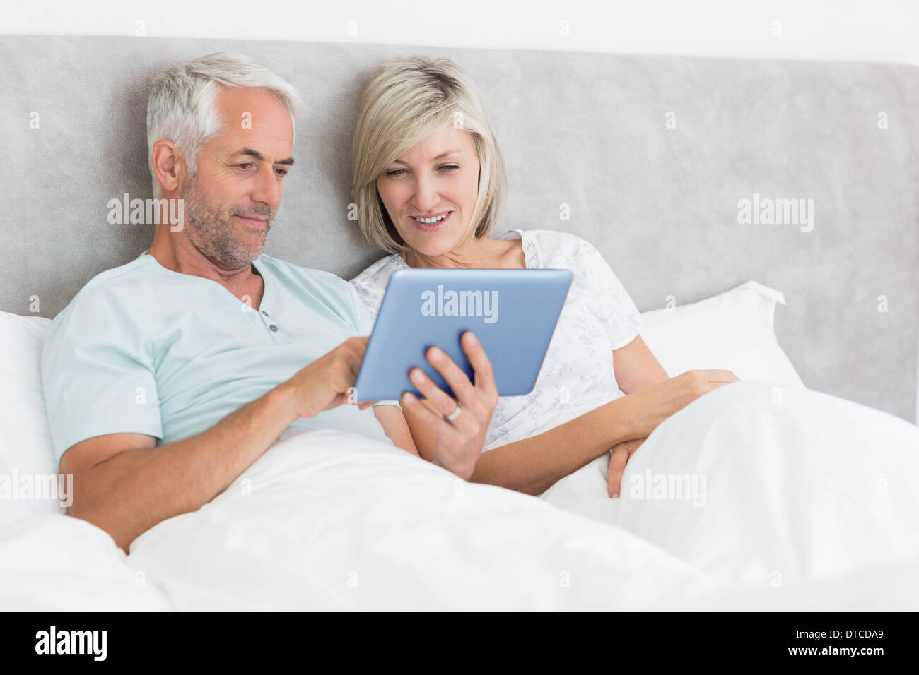 Coppia felice con tavoletta digitale a letto Foto Stock